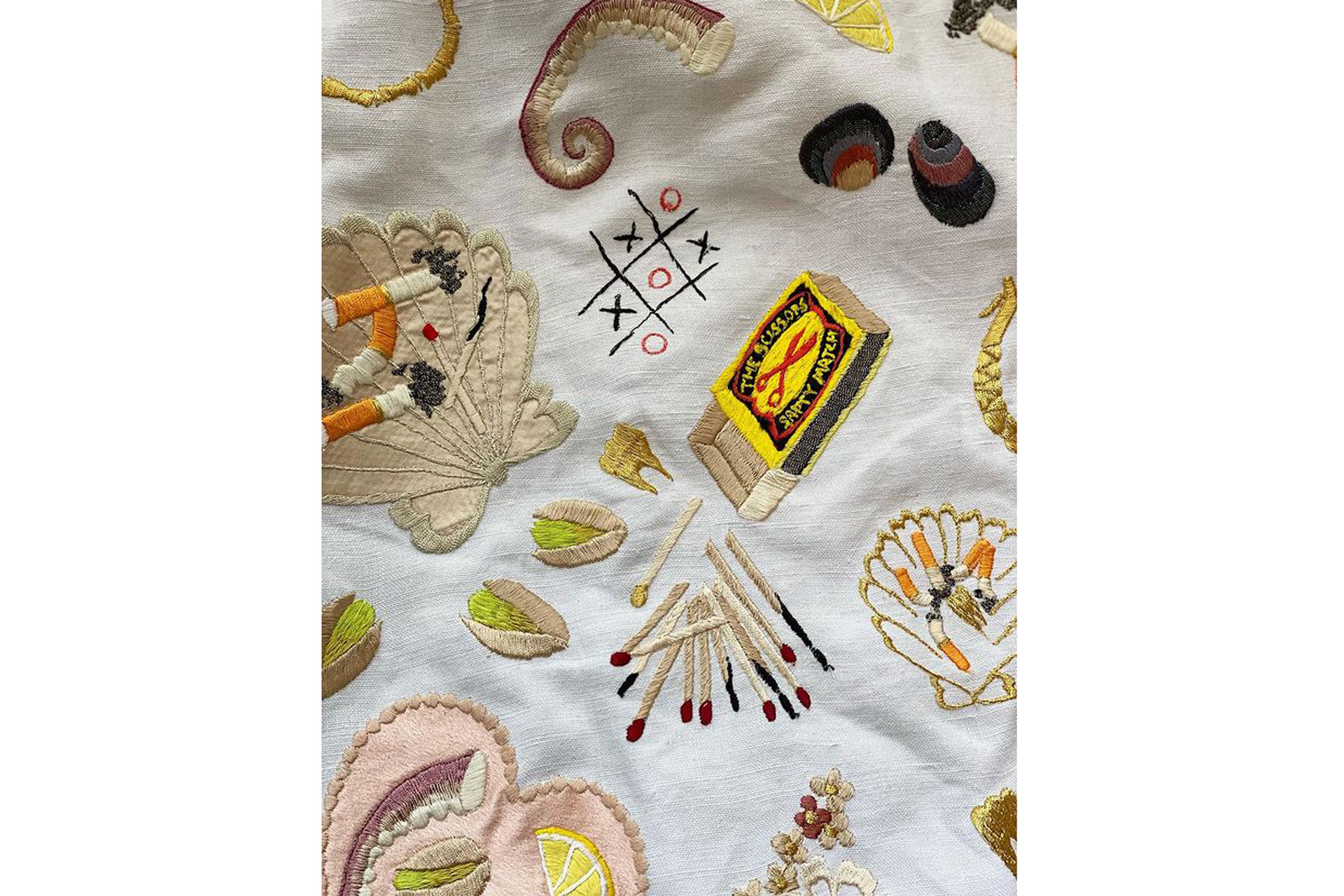 embroidered tablecloth with images of matchbox matchsticks and octopus tentacles