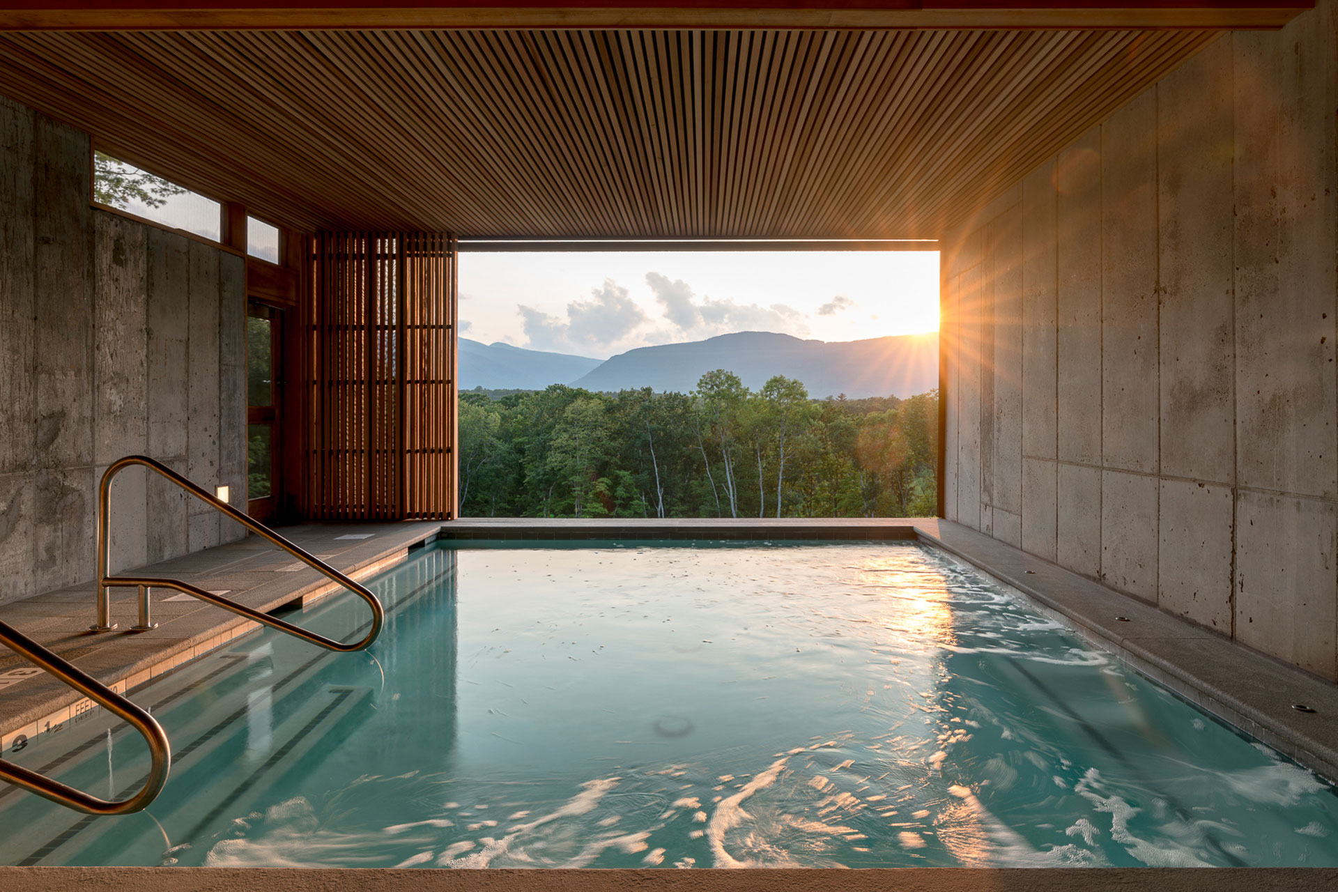 A swimming pool overlooking a sunset and rainforest Piaule Catskill hotel