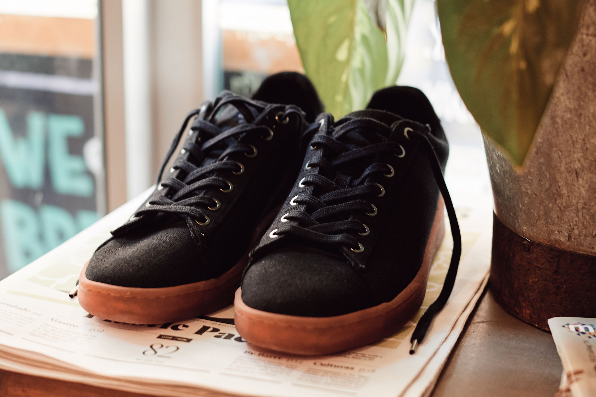 a pair of black waes canvas trainers on a newspaper