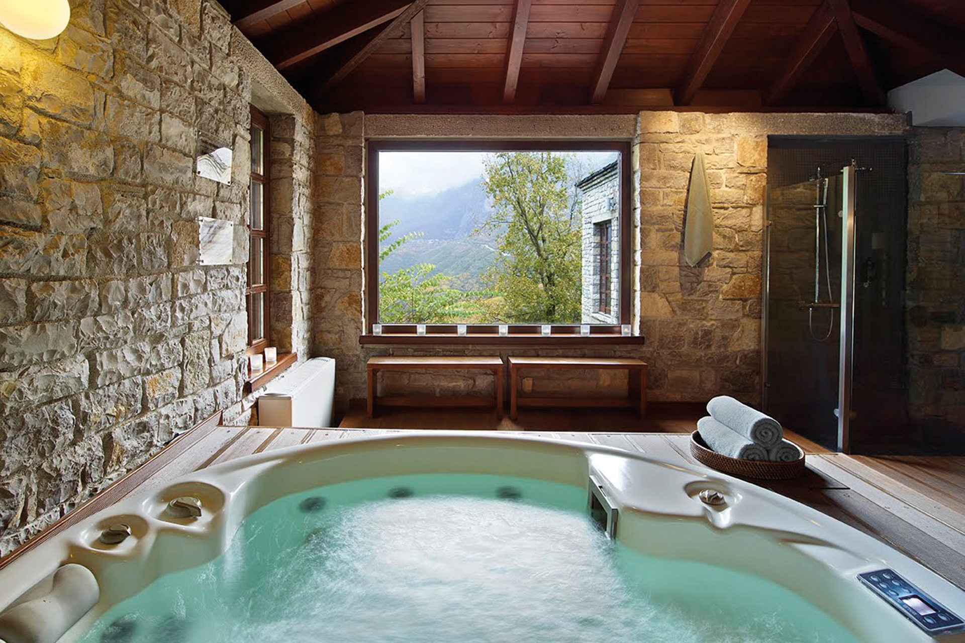 A hot tub in a wood-ceiling room looking onto trees