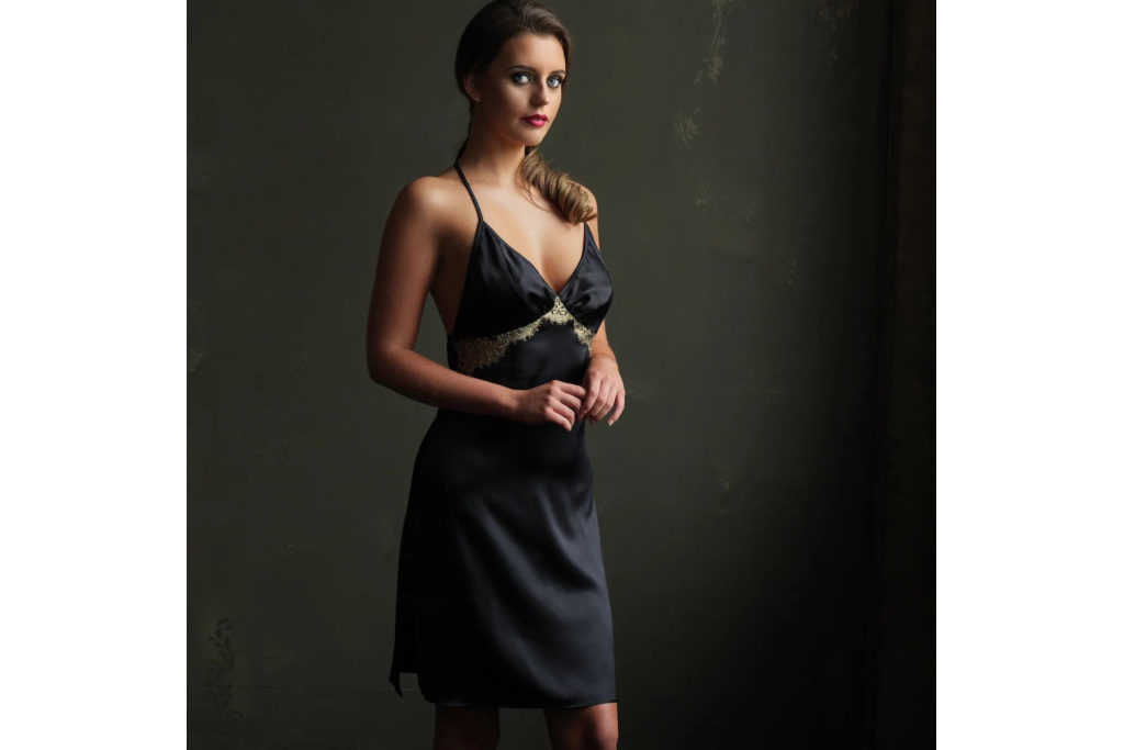 Woman stood in black slip in front of dark grey background