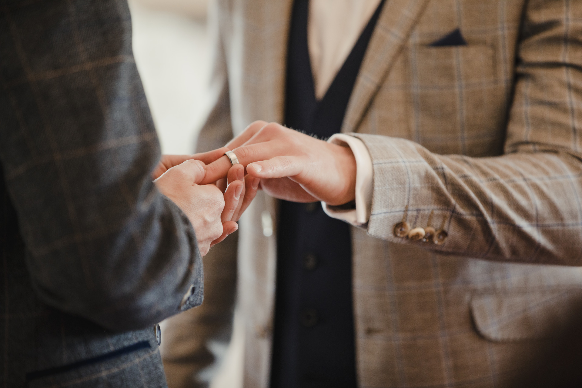 Two men are exchanging rings on their wedding day.