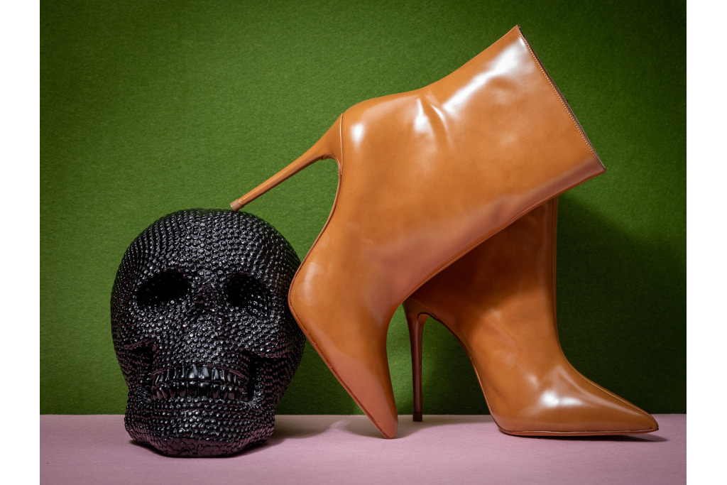 A pair of brown boots leaning against a black jewelled skull