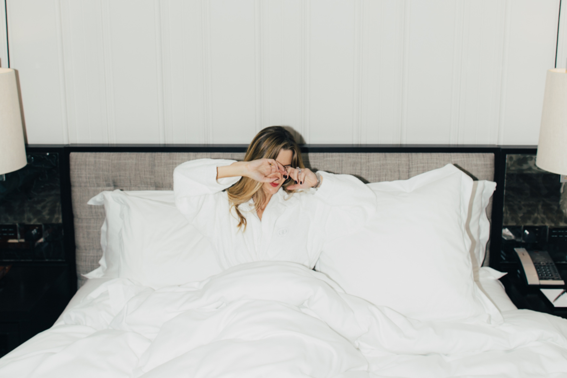 sleepy woman in bed white duvet rosewood hotel