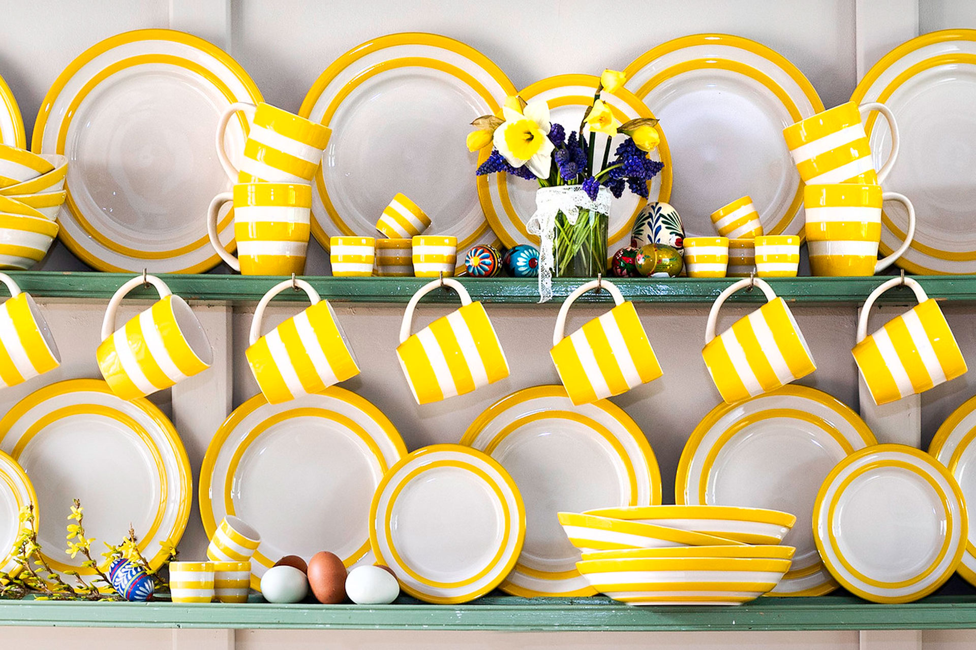 A dresser withyellow stripy mugs and plates by Cornishware