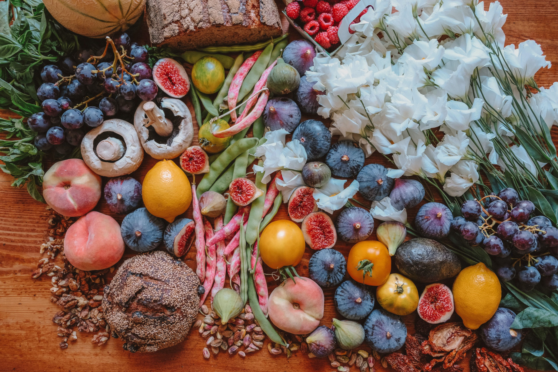 Table covered in fruit, vegetables and flowers