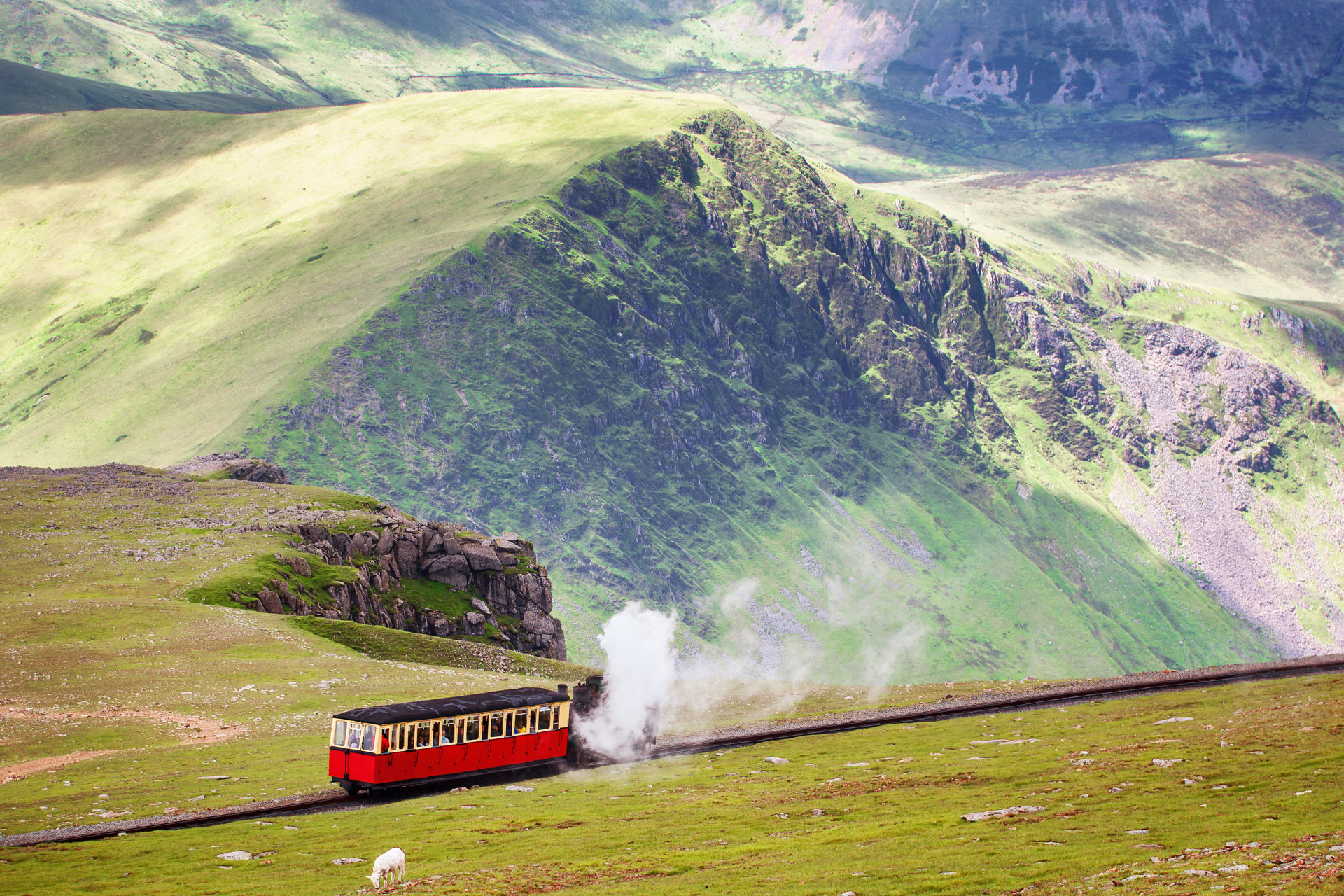 a red train crosses a Scottish landscape