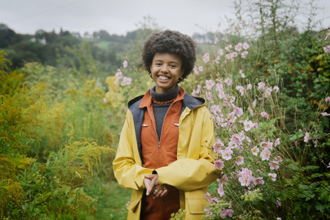ecologist Poppy Okotcha stands smiling in a garden