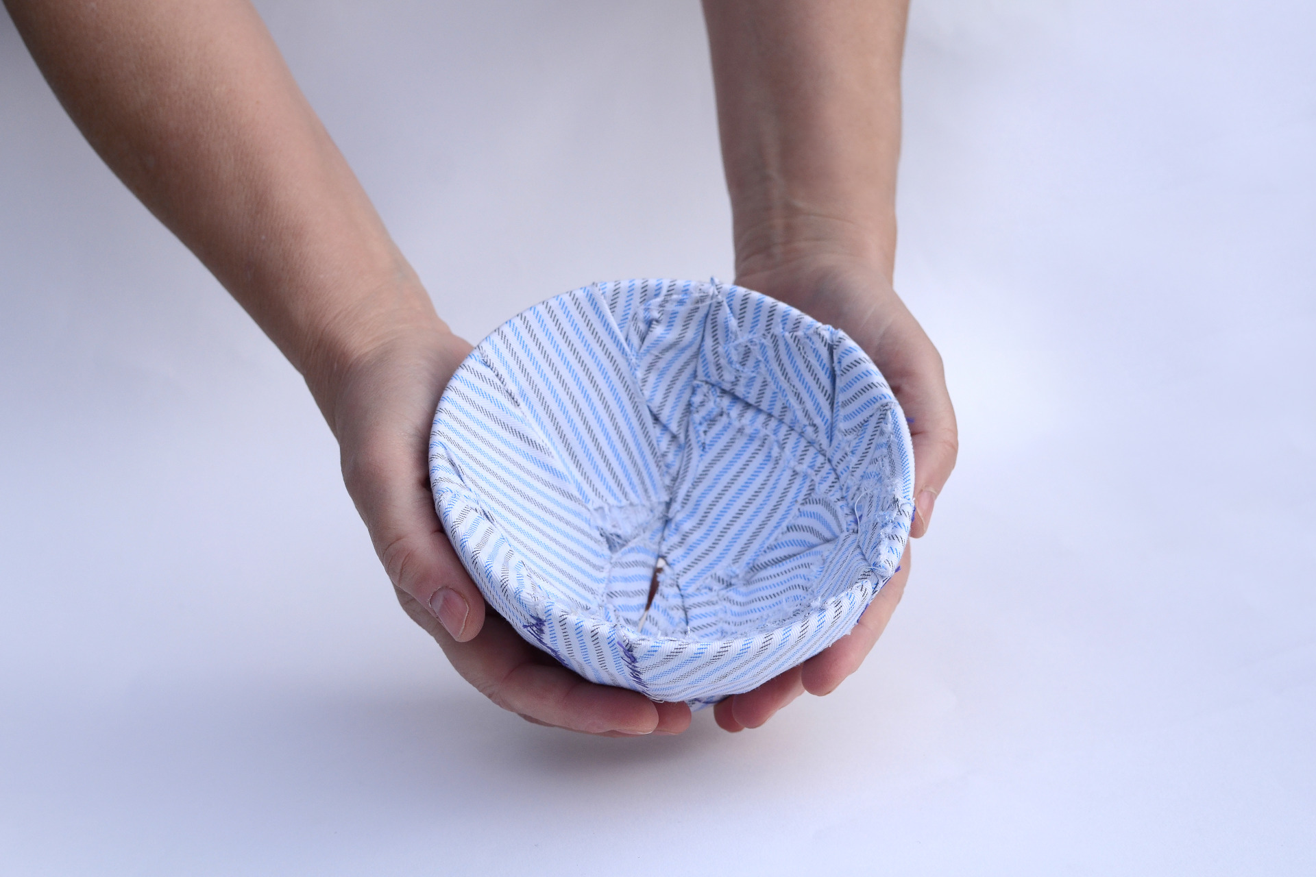 Hands holding a broken bowl pieced back together