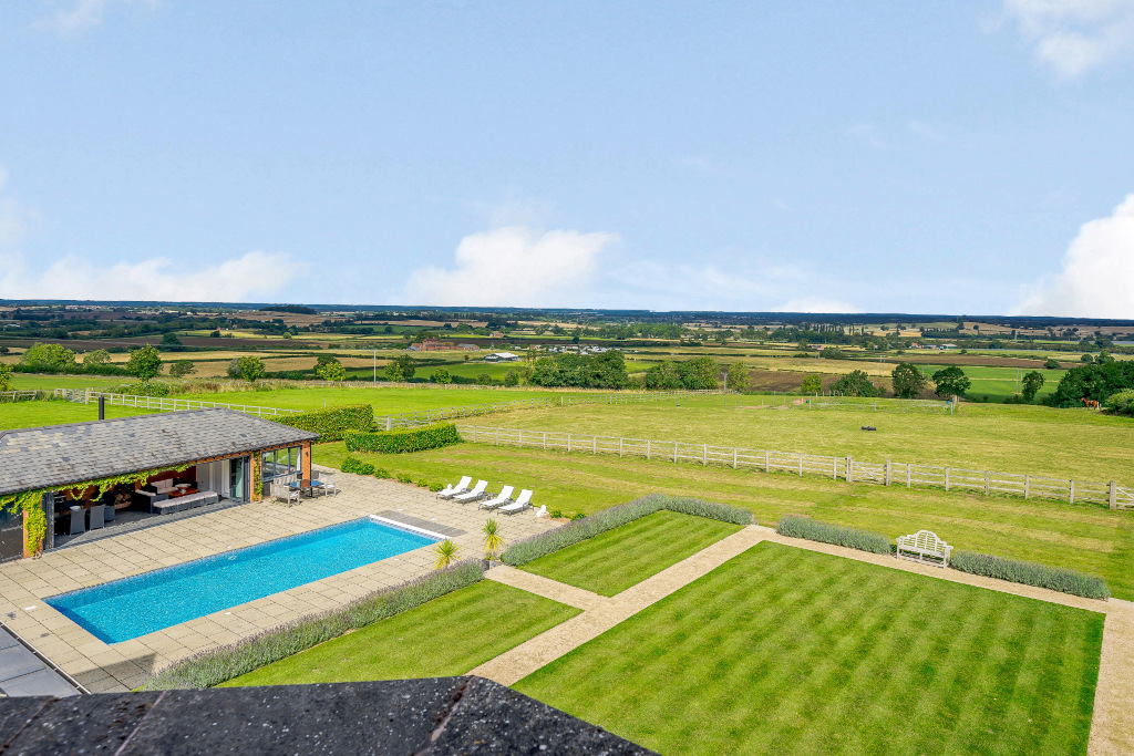 shot of swimming pool, gardens, grassy fields and countryside