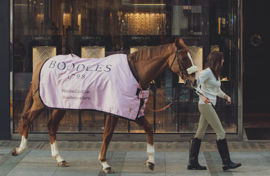 Jockey Rachel Blackmore leads racehorse wearing Boodles branded pink rug