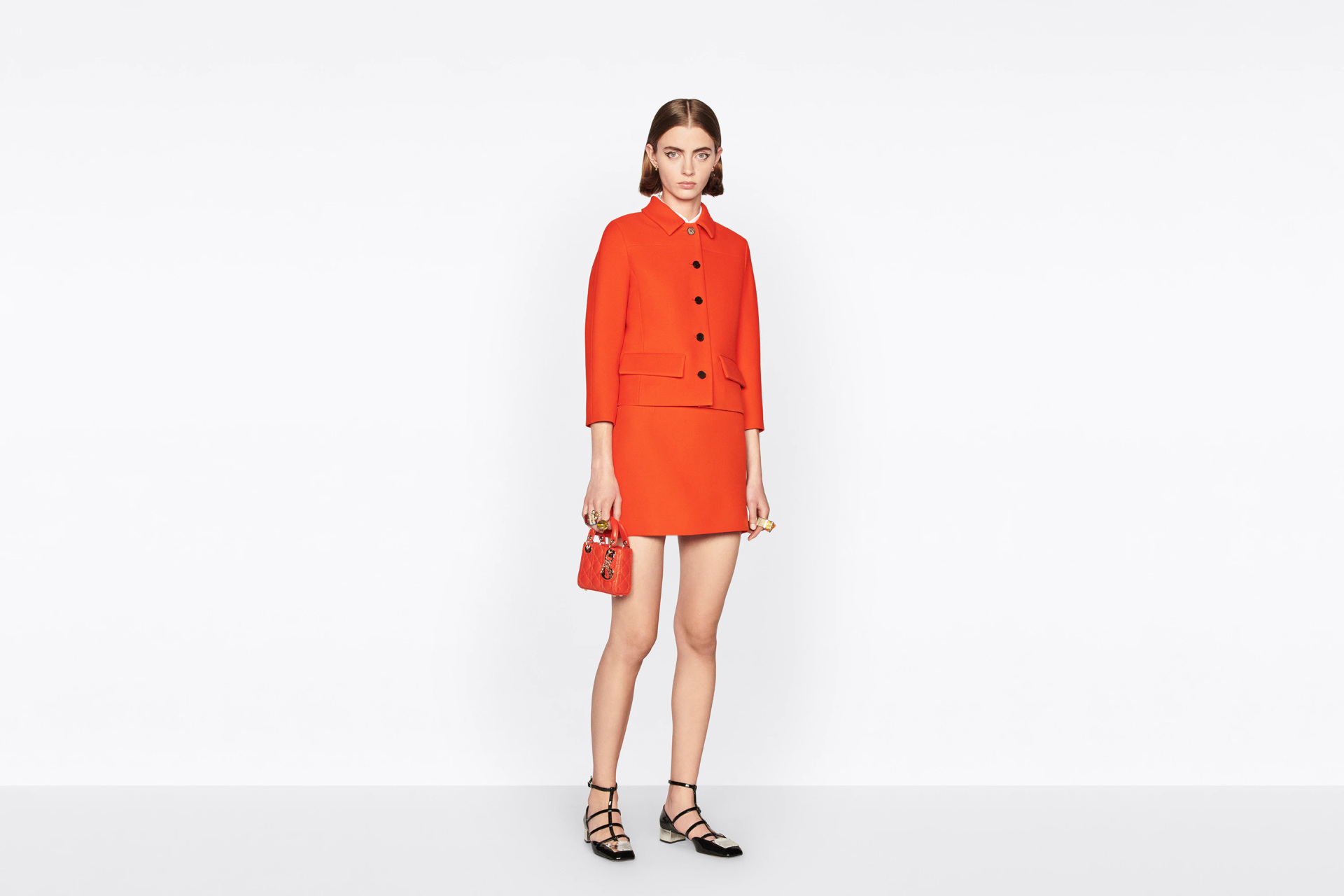 Model in orange miniskirt suit on plain white background