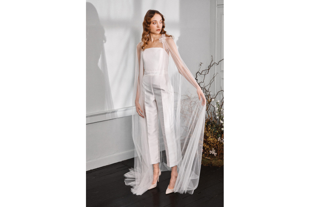 Model in ivory corset, trousers and tulle cape