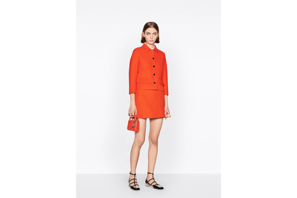 Model in orange miniskirt suit on plain white background
