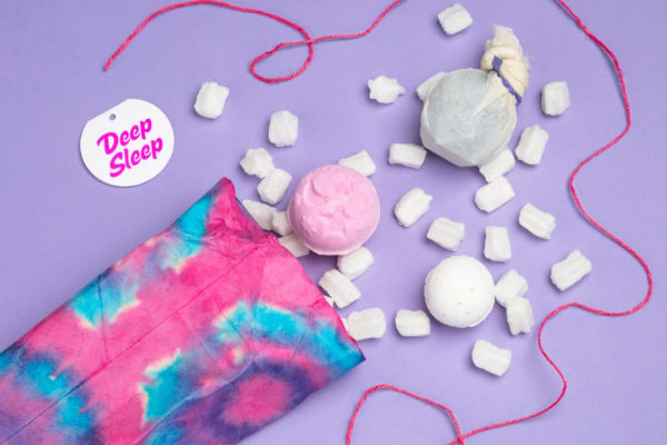 Pink package with bath bomb and pink string on purple background
