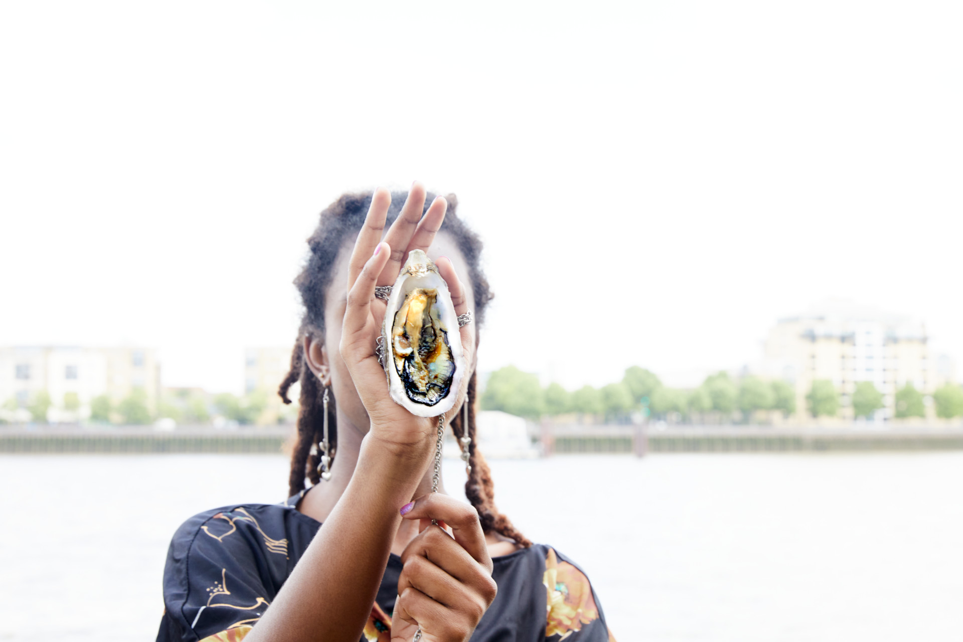 Woman holding up a shell pendant in front of her face