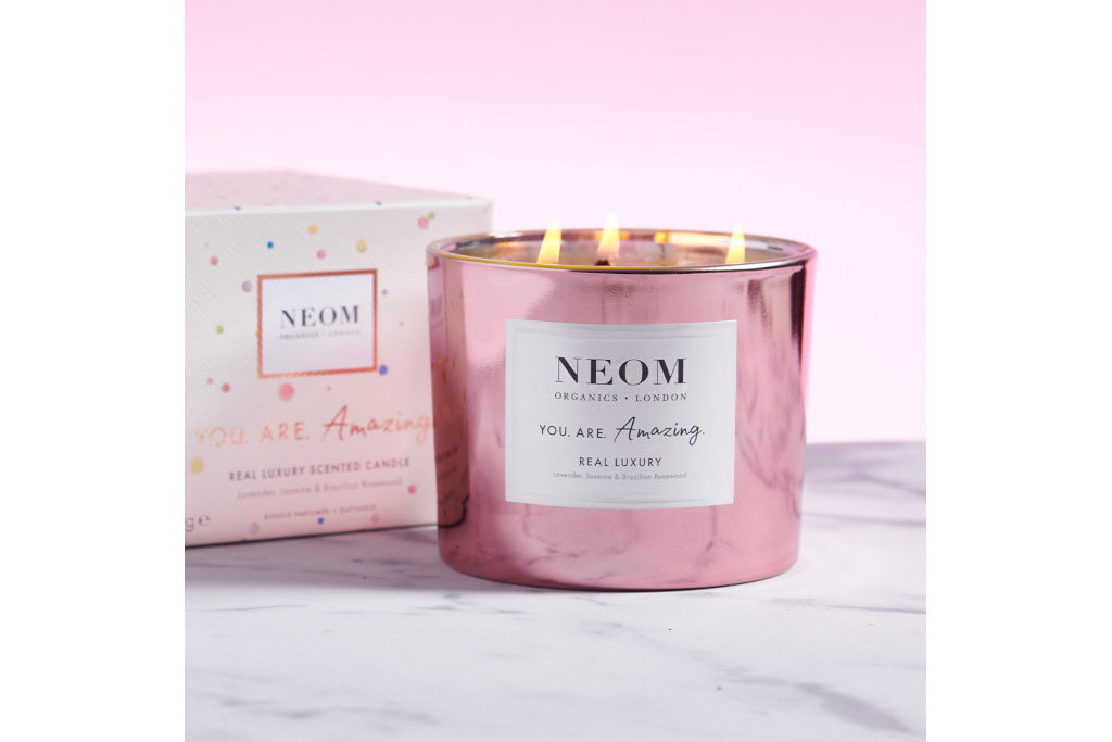 Candle in pink metallic jar with gift box behind it