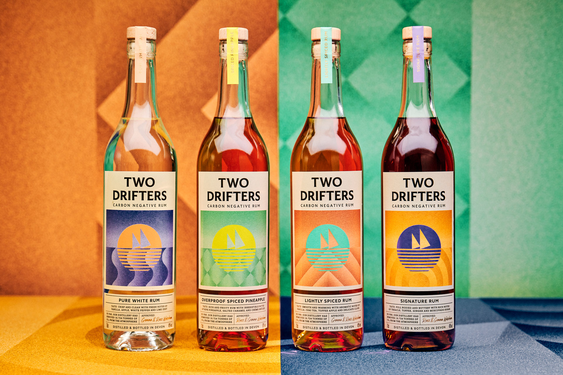 Four bottles of rum lined up on front of multicoloured background