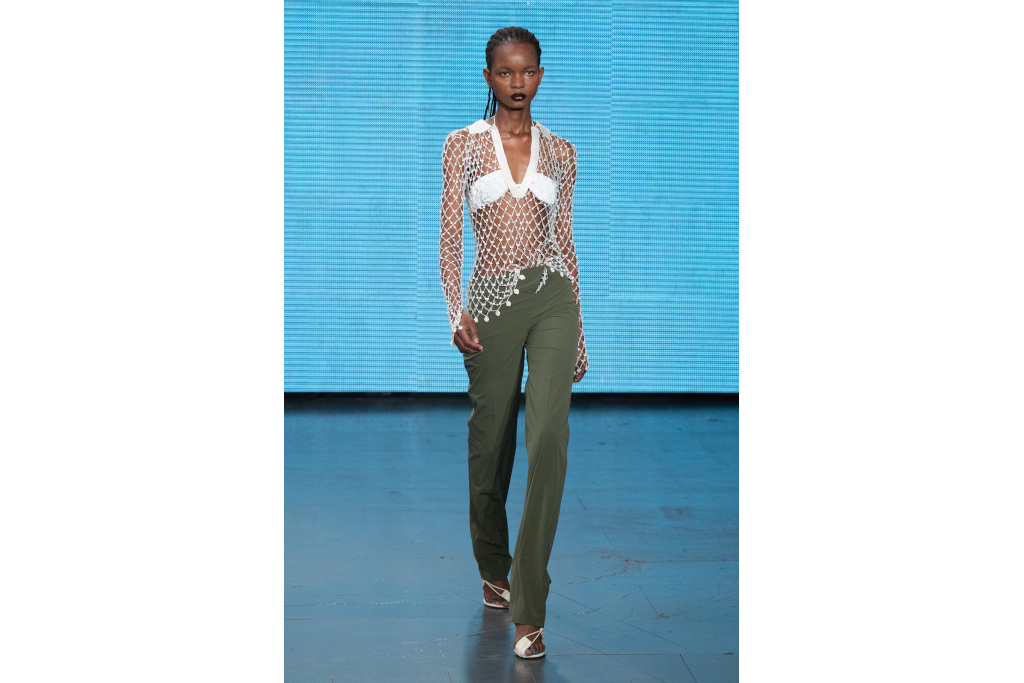 Model in green trousers and white net top