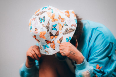 Model wearing a butterfly print bucket hat and blue jumper