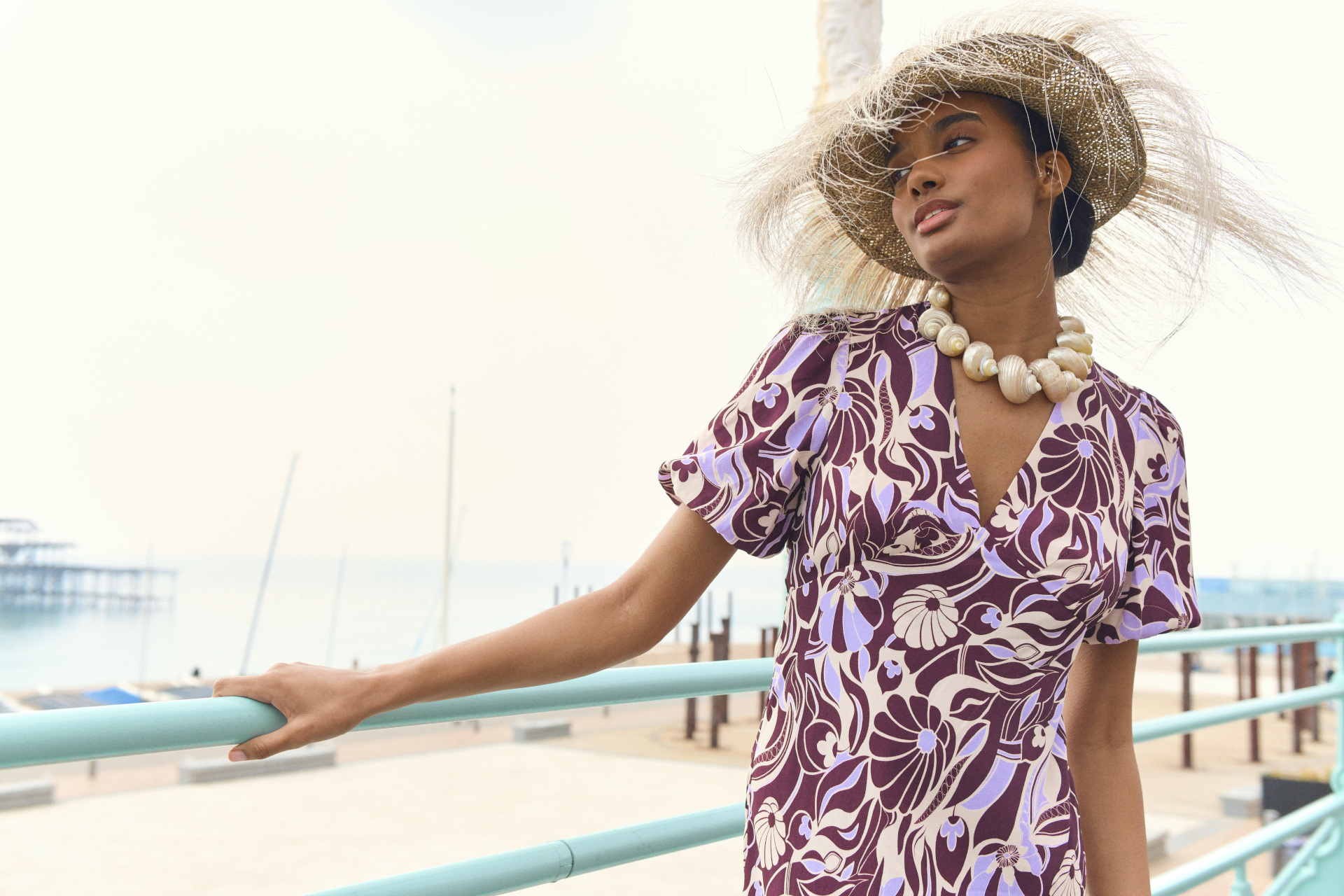 Model in purple dress wearing woven hat