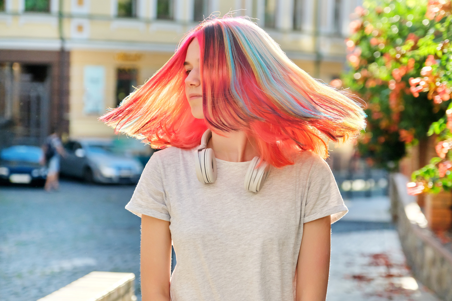 Close-up of fluttering colored dyed hair of young woman on sunny city street