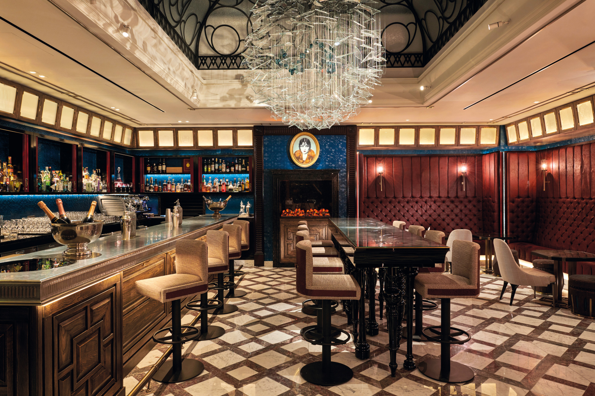 Low-lit bar with chandeliers, tiled floors and red panelled walls