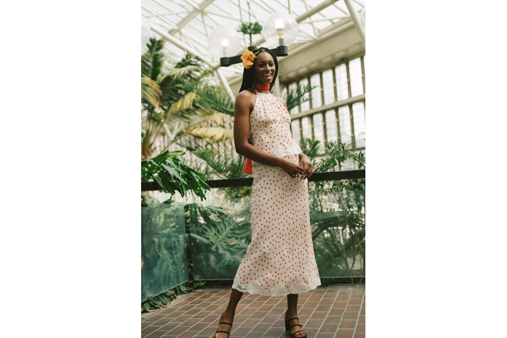 Model in white top and skirt with red spots