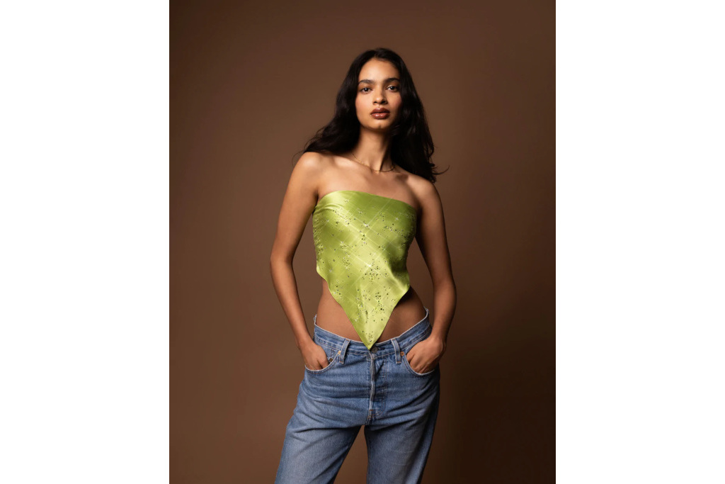 Model in green scarf top and baggy jeans, stood in front of brown background
