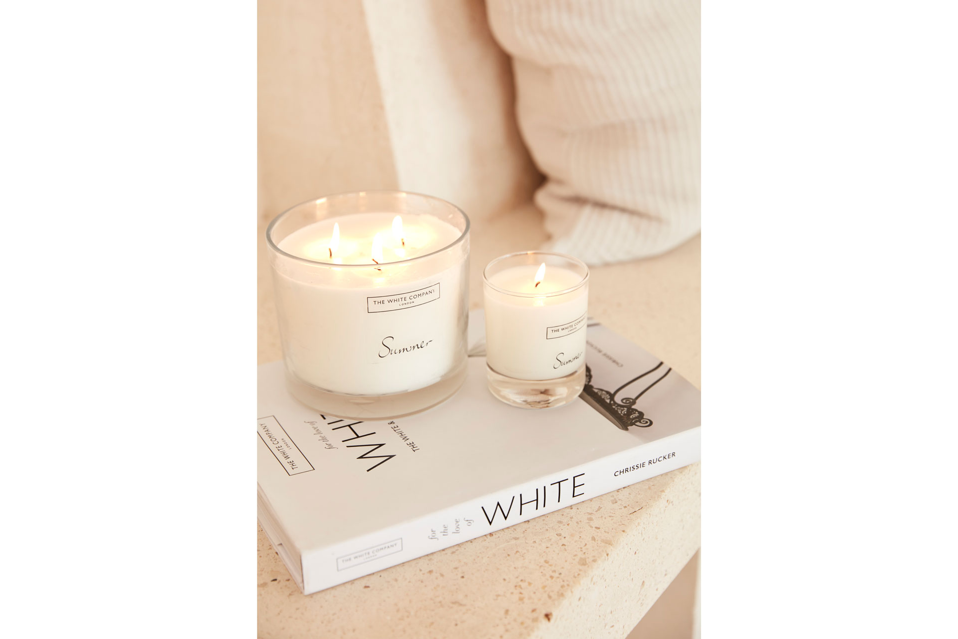Two large candles by The White Company stand on a magazine