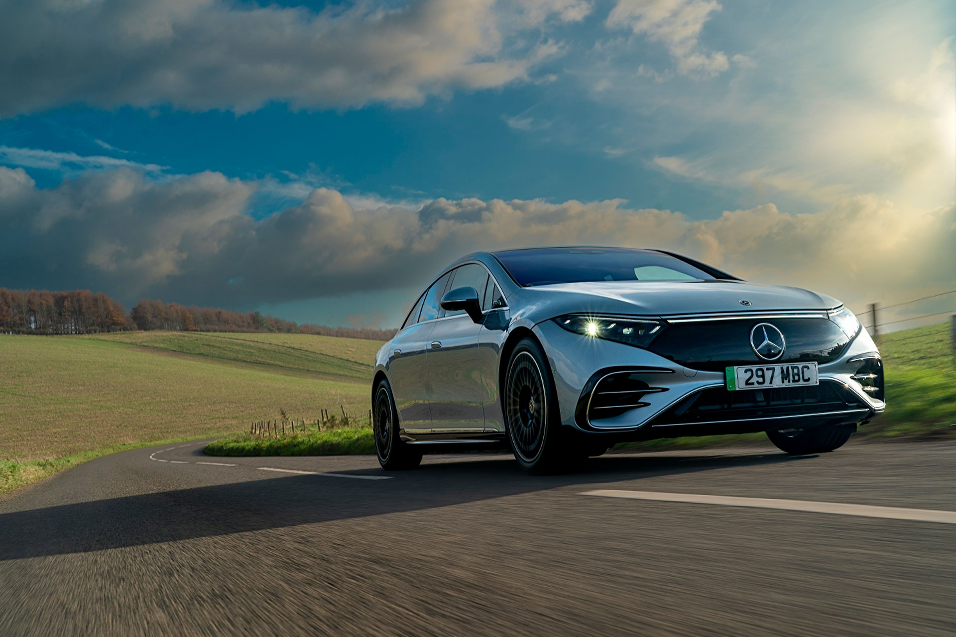 Mercedes EQS driving on a hill in a green landscape