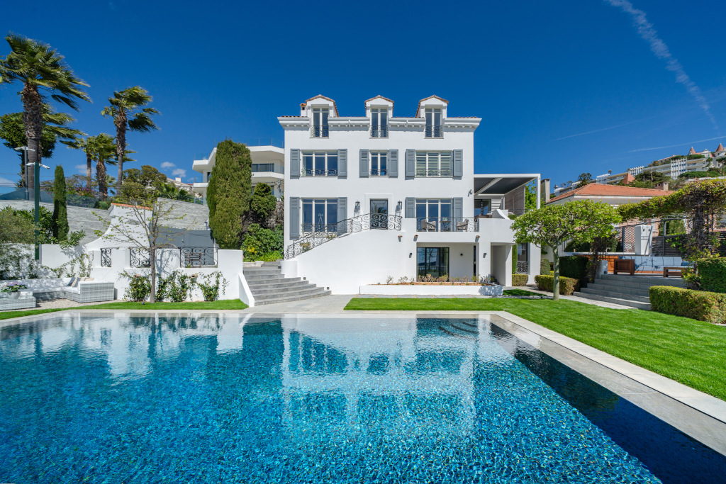 exterior shot of estee lauder former white french villa with blue shutters and swimming pool 
