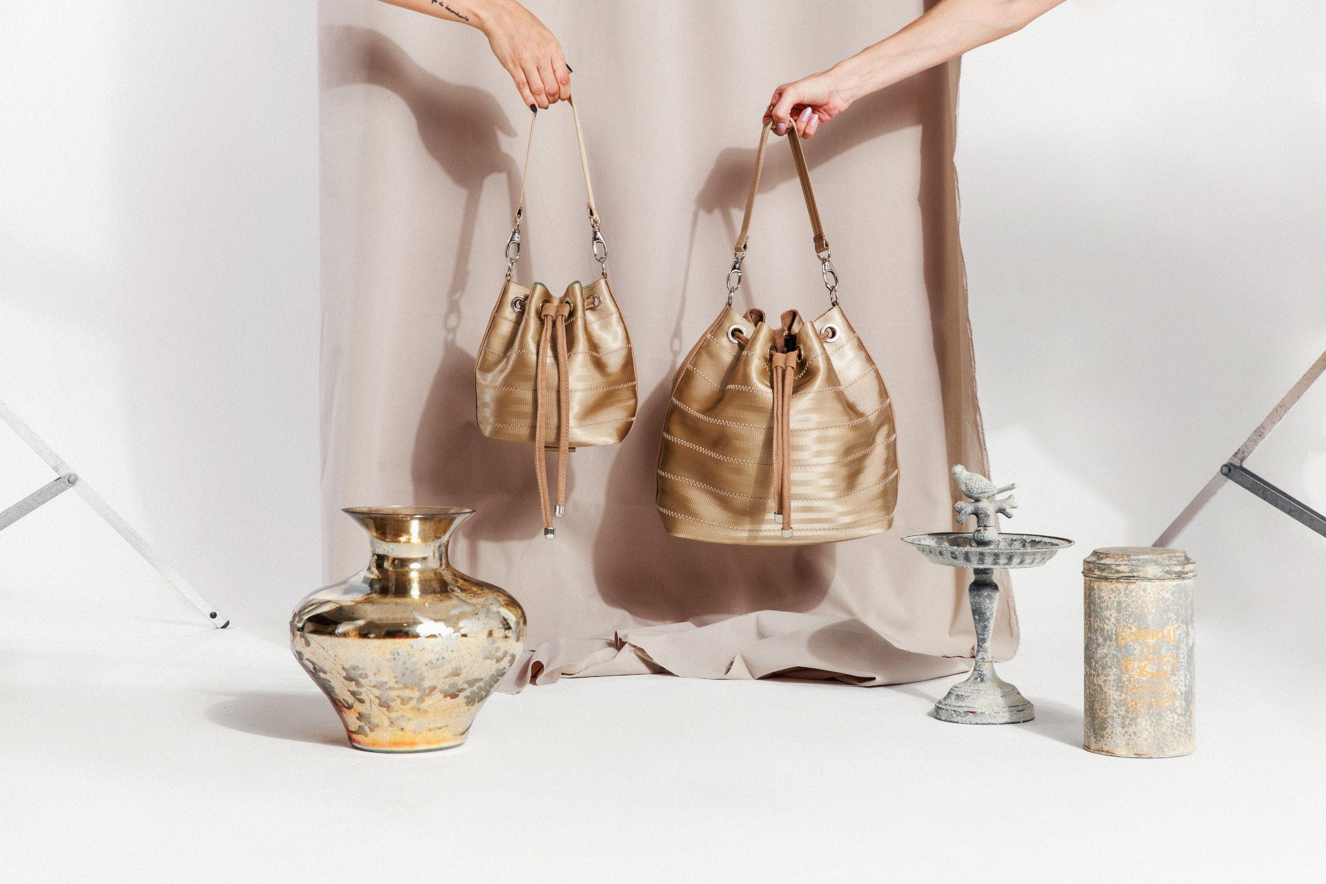 Two gold bucket bags on photo shoot set with gold vases and candle holders