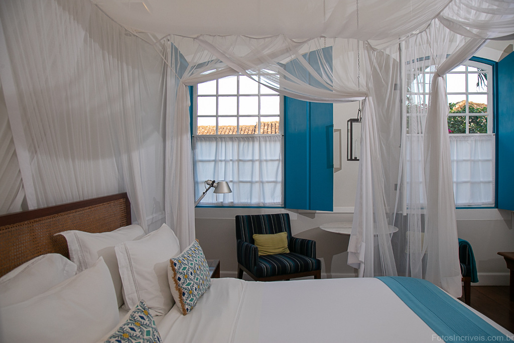 hotel bedroom with white and blue decor and ocean view