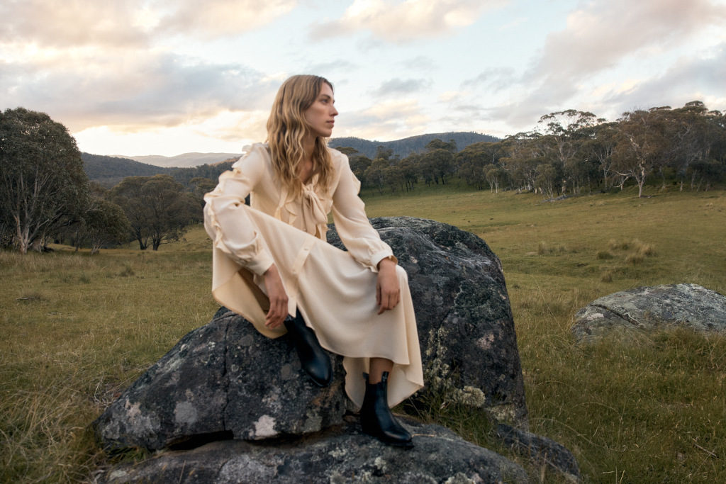 woman wearing cream long ruffled dress on a rock in australian countryside, cottagecore