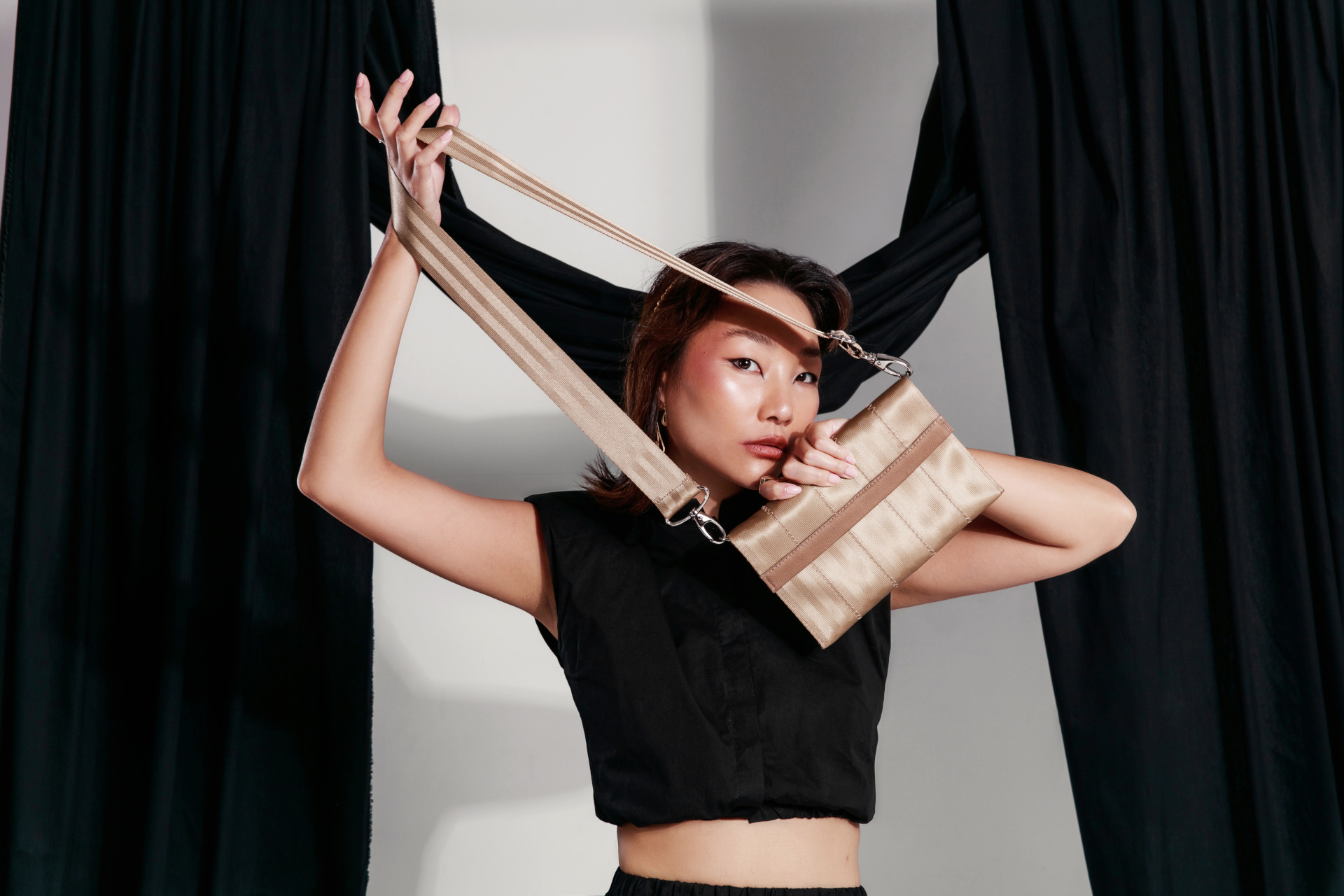 Model holding gold handbag made from seatbelts
