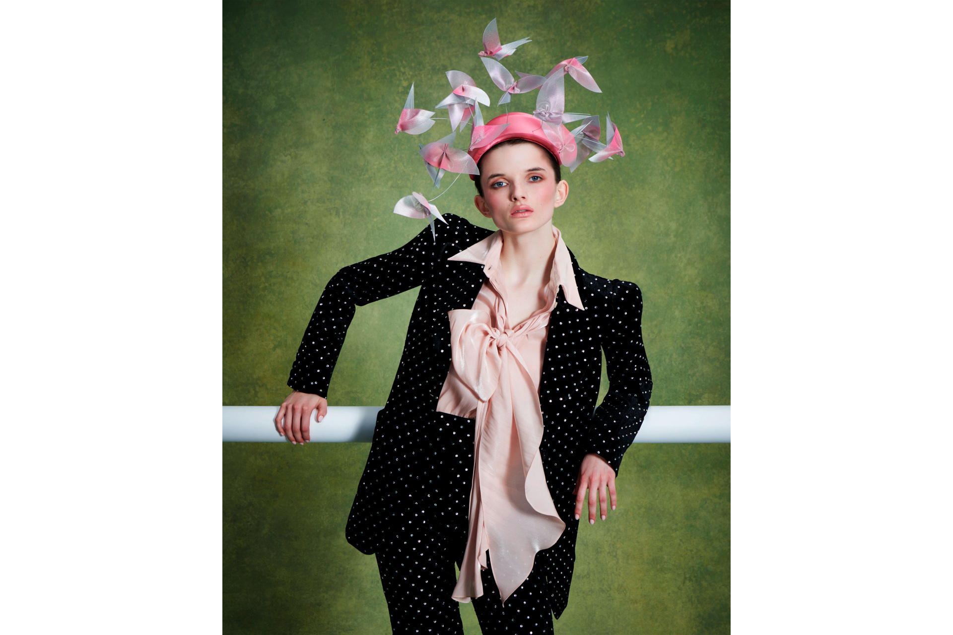 Woman in black suit with pink shirt and headpiece
