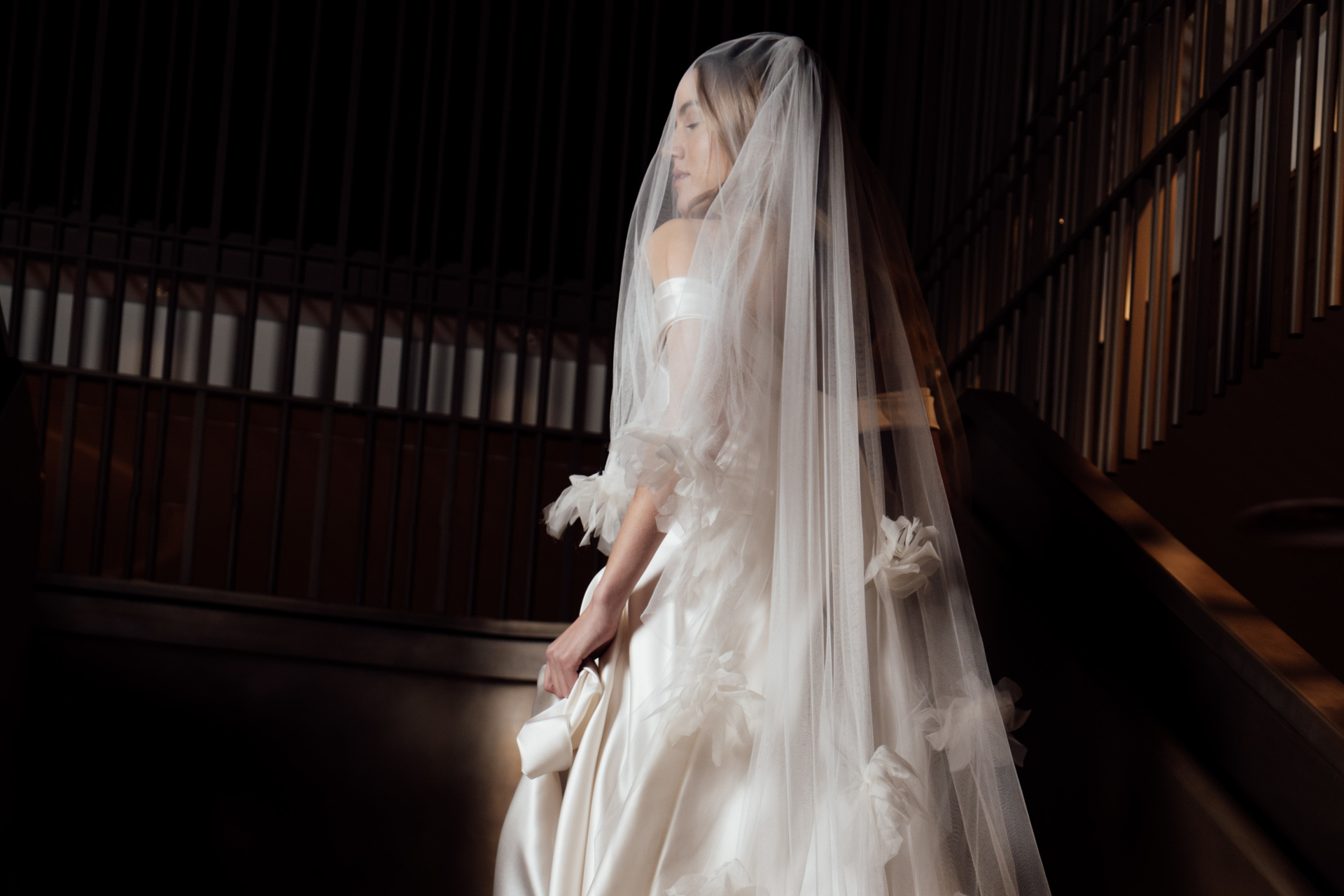 Model walking upstairs in trailing bridal veil and wedding dress