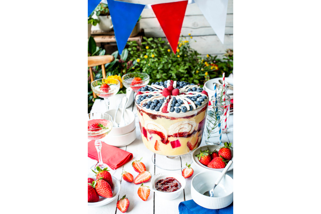 Union Jack trifle on table with strawberries, plates and glasses