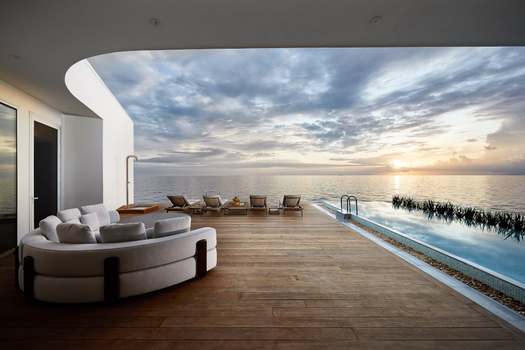 decking with pool, sofas and sun beds overlooking the ocean at sunset