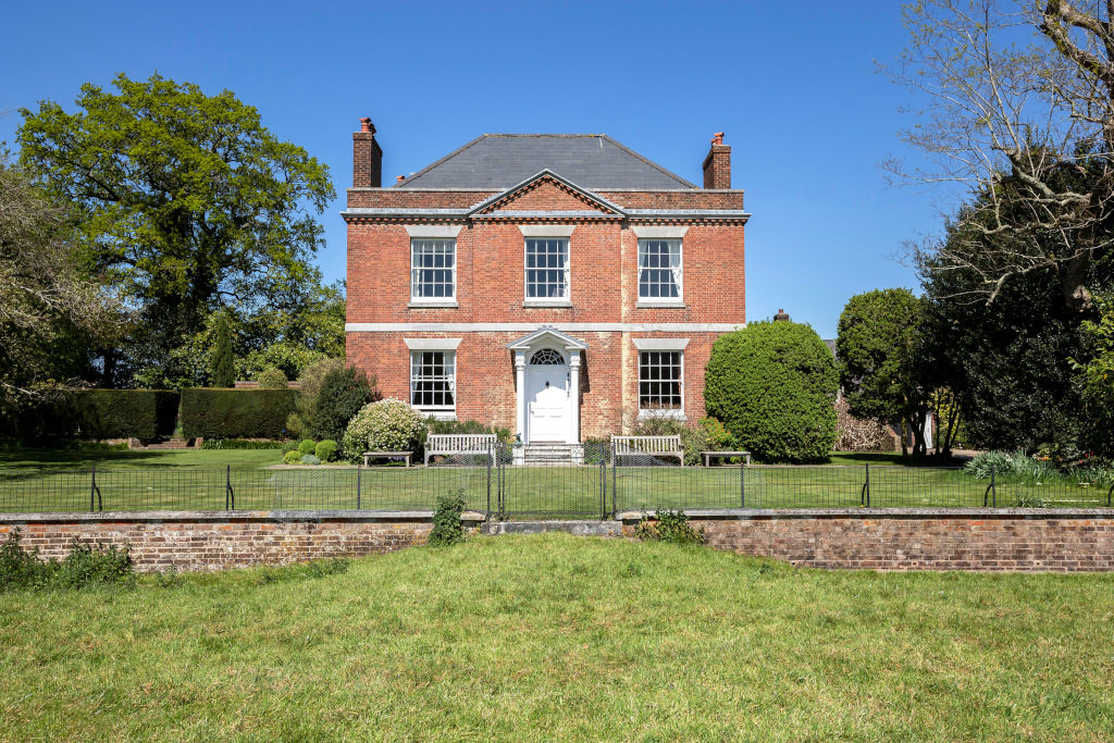 red brick georgian property house with white windows and white front door overlooking gardens