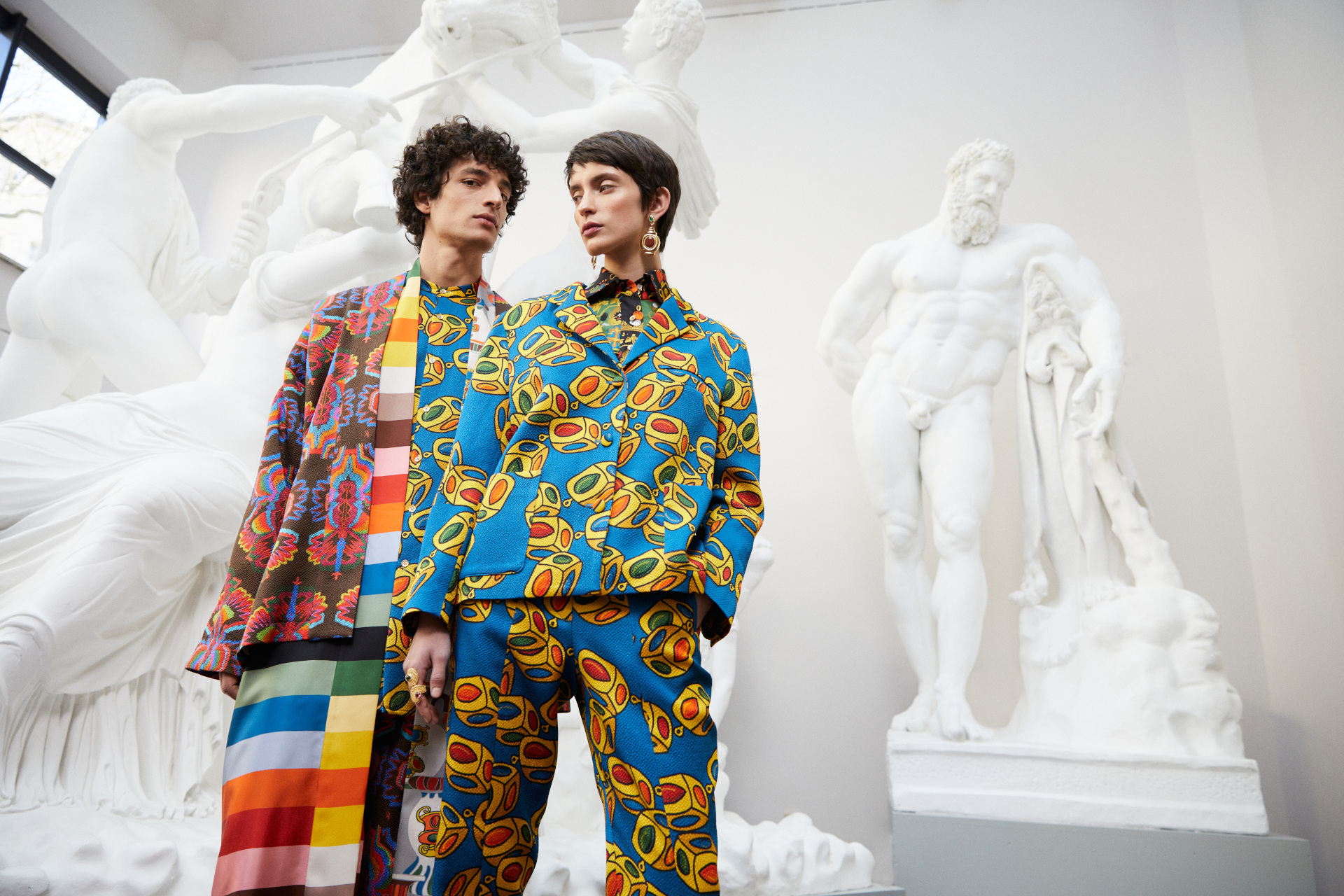 Two models in one-of-a-kind fashion stood in a sculpture gallery