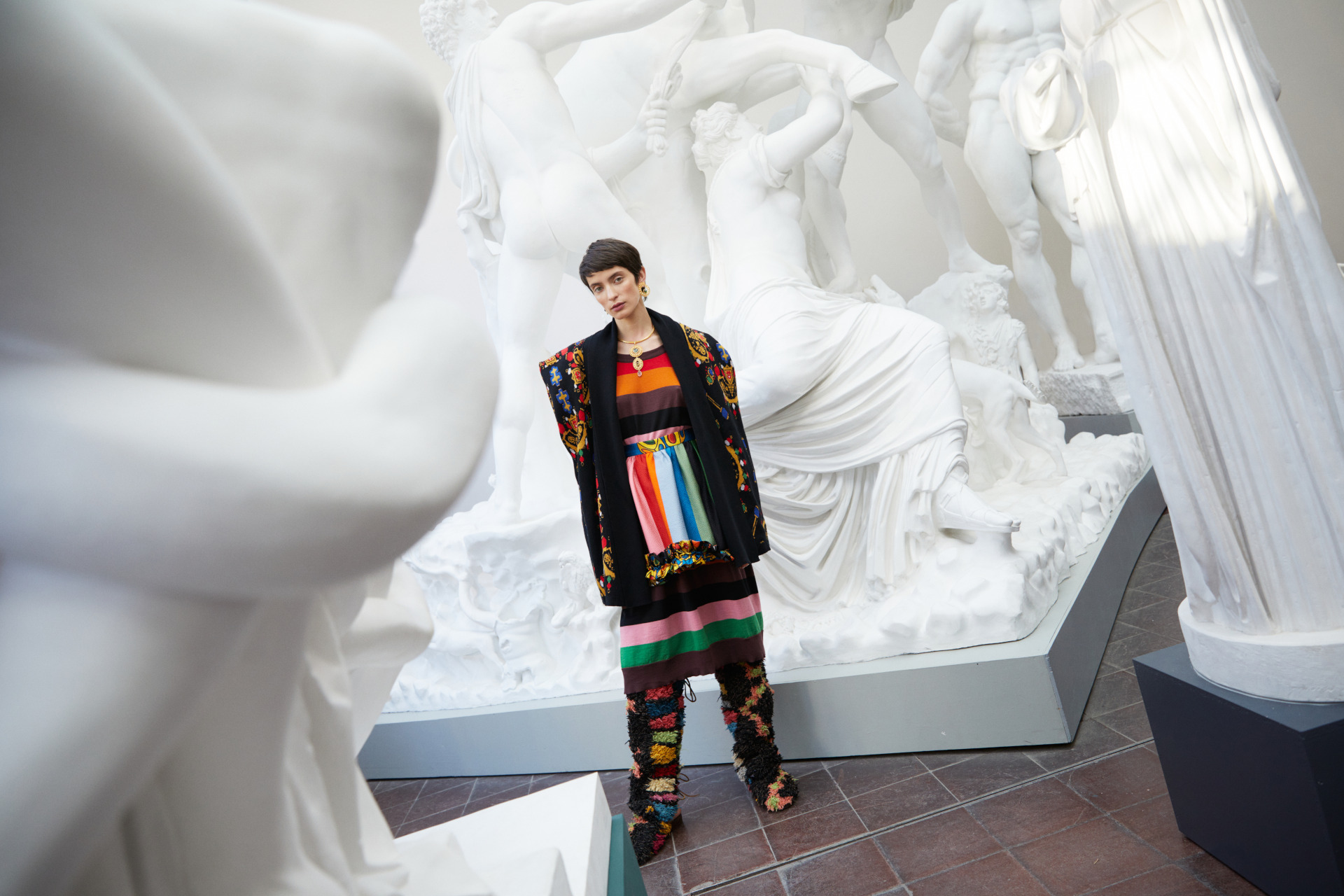 Model in one-of-a-kind fashion stood in a sculpture gallery