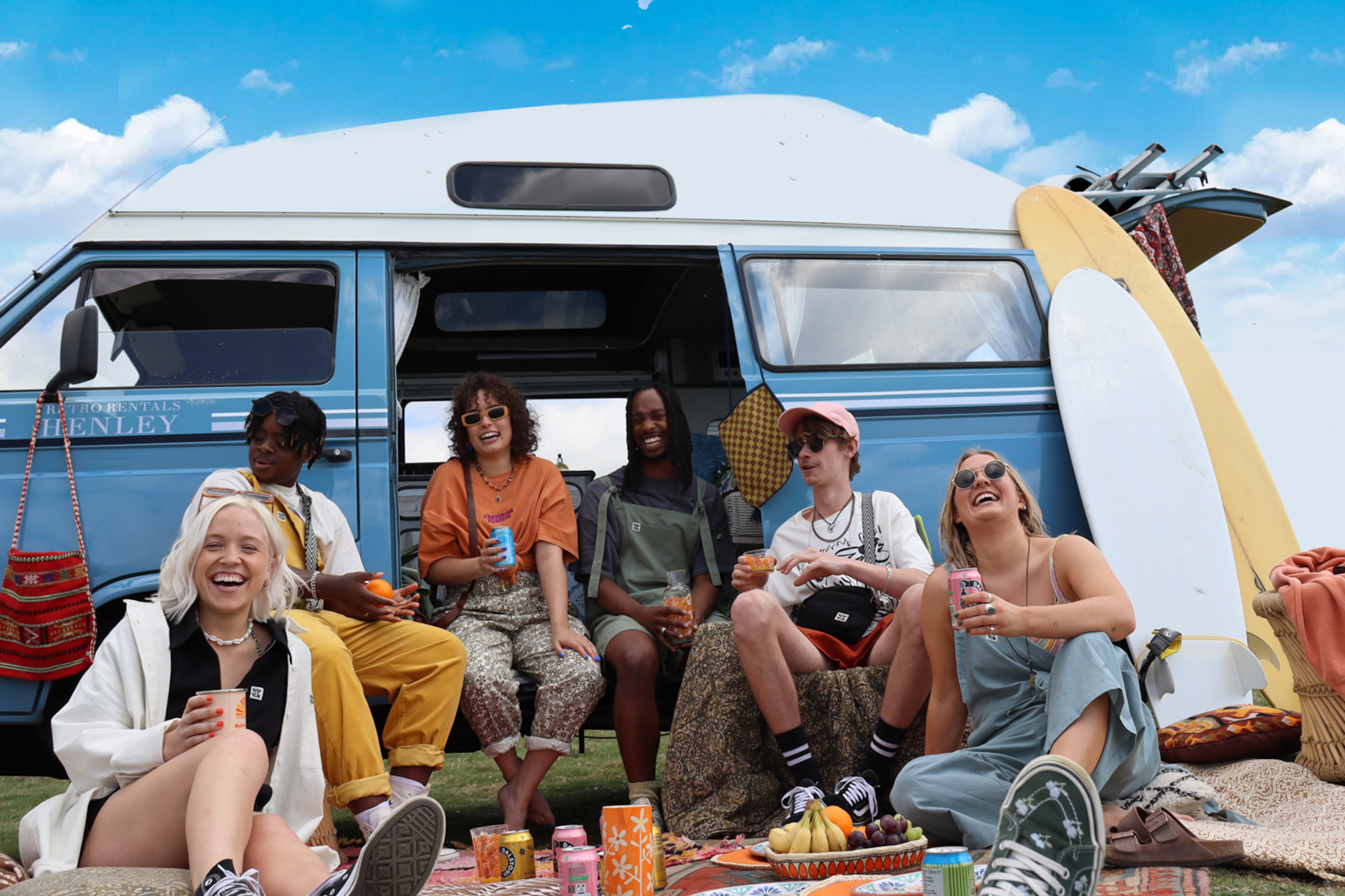 Young people in dungarees sat in front of camper van in summer