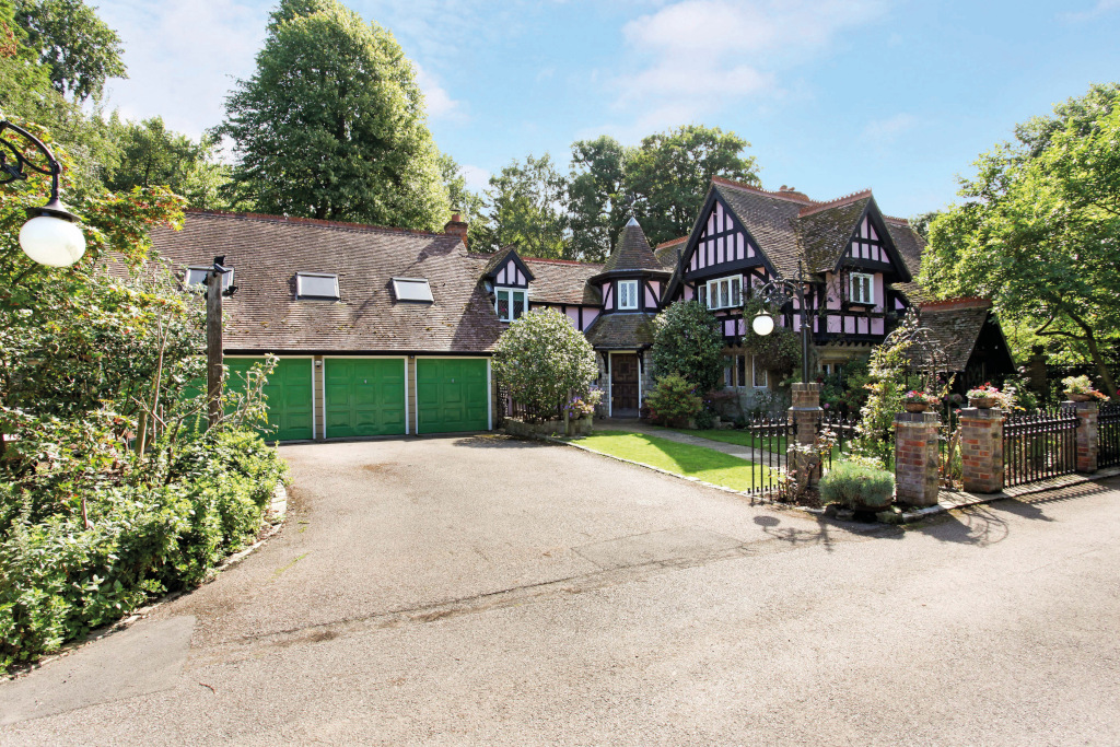 pink tudor property from driveway with green garage