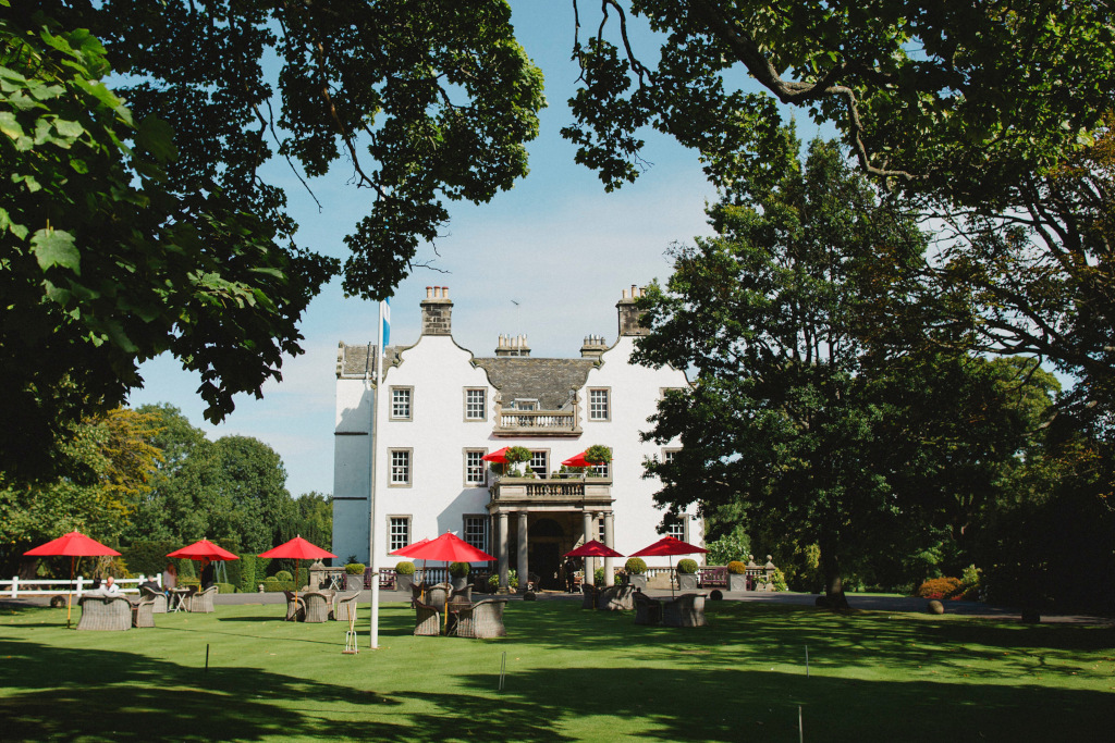 prestonfield exterior white hotel with garden and red umbrella tables