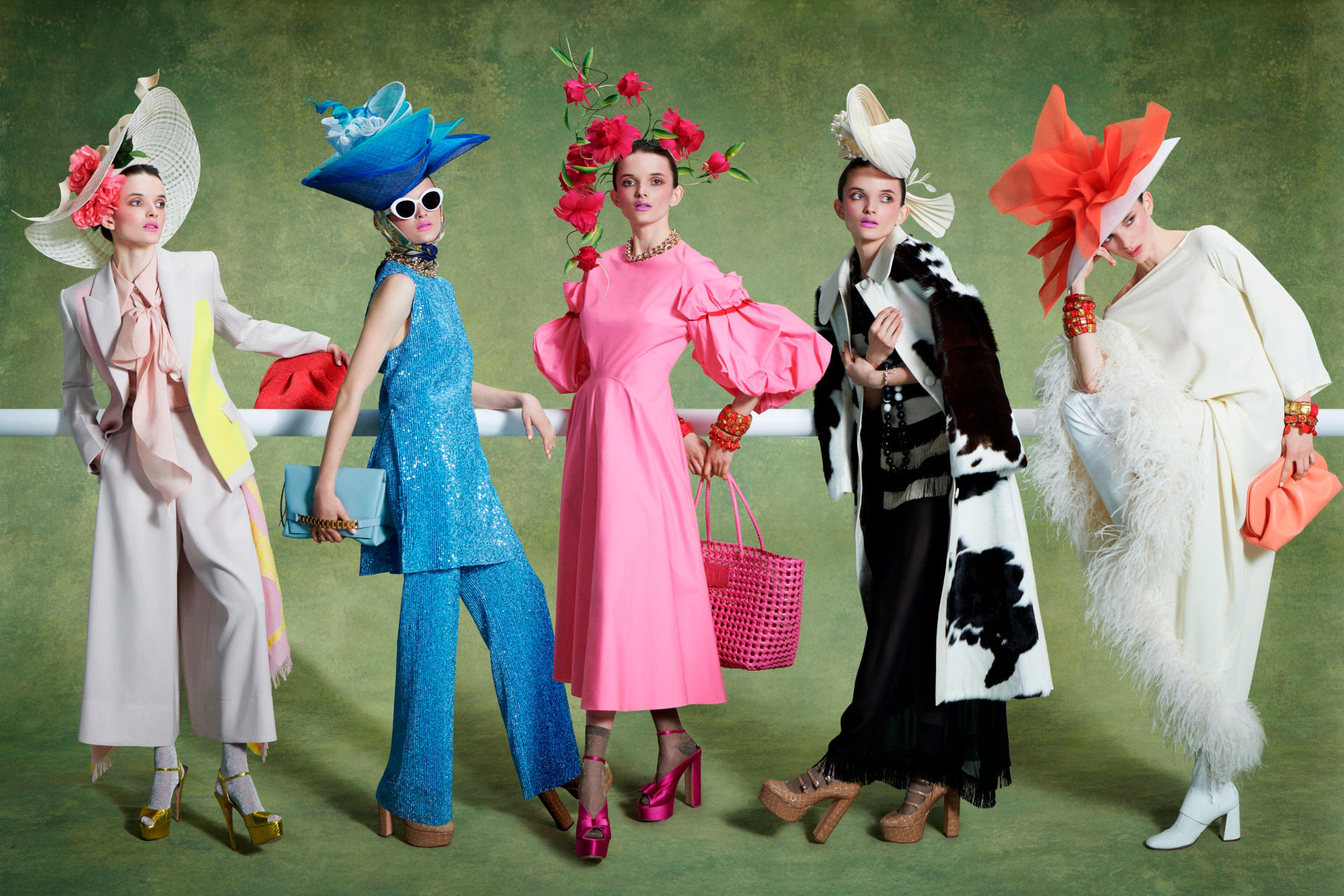 Woman lined up in colourful outfits and grand hats