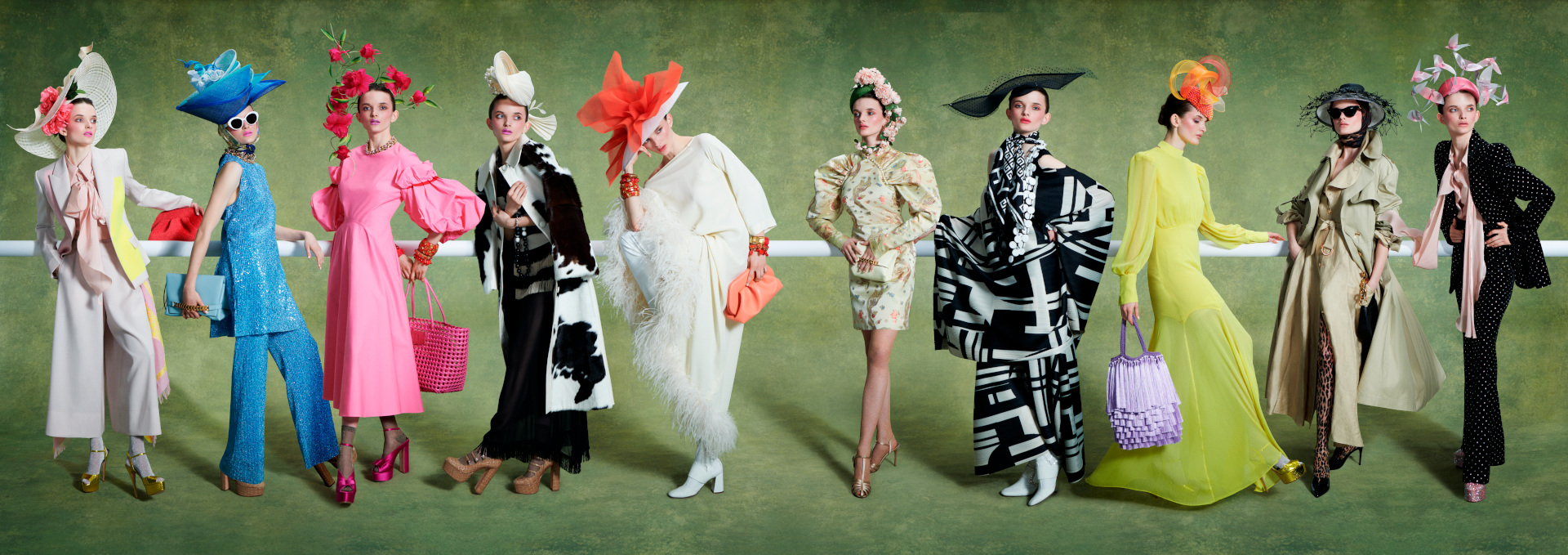 Woman lined up in colourful outfits and grand hats