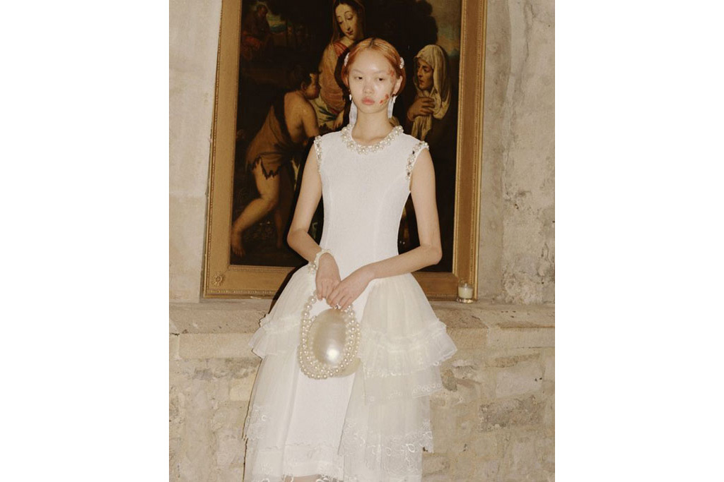 Model in white dress holding pearl bag