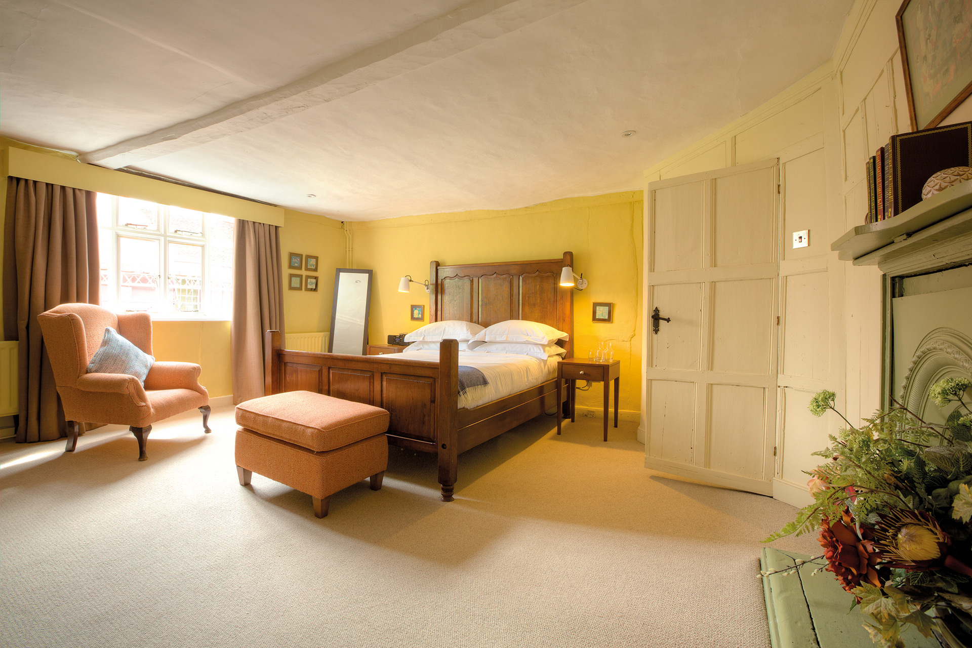 Bedroom at the Sun Inn with a yellow feature wall and dark wooden bedframe.